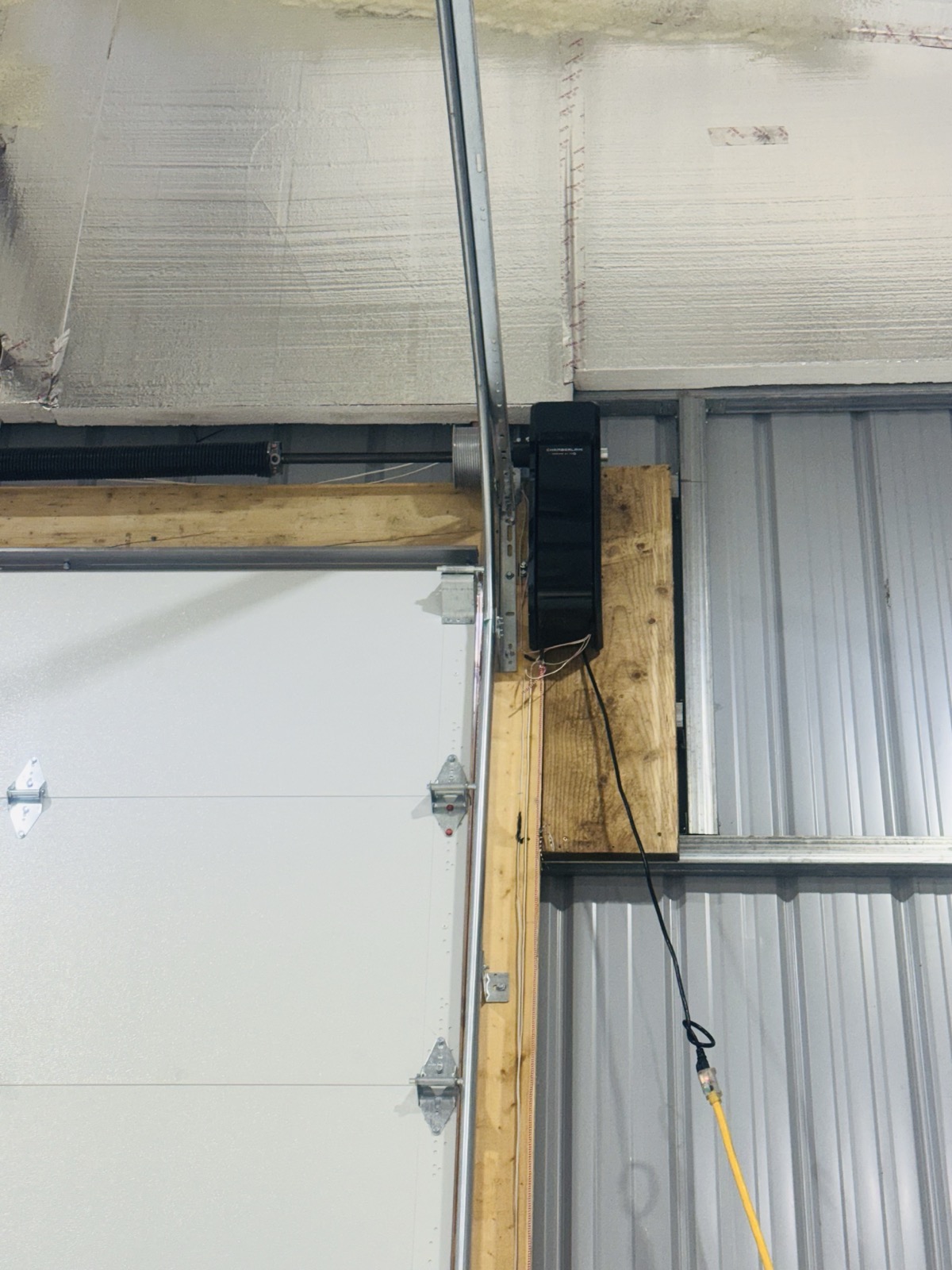 Commercial garage door opener mounted to wood blocking inside a metal building