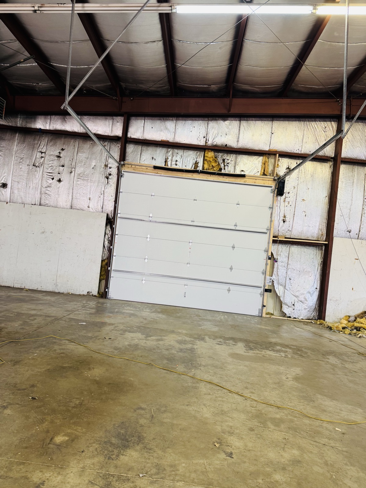 Large commercial garage door installed inside a metal warehouse building