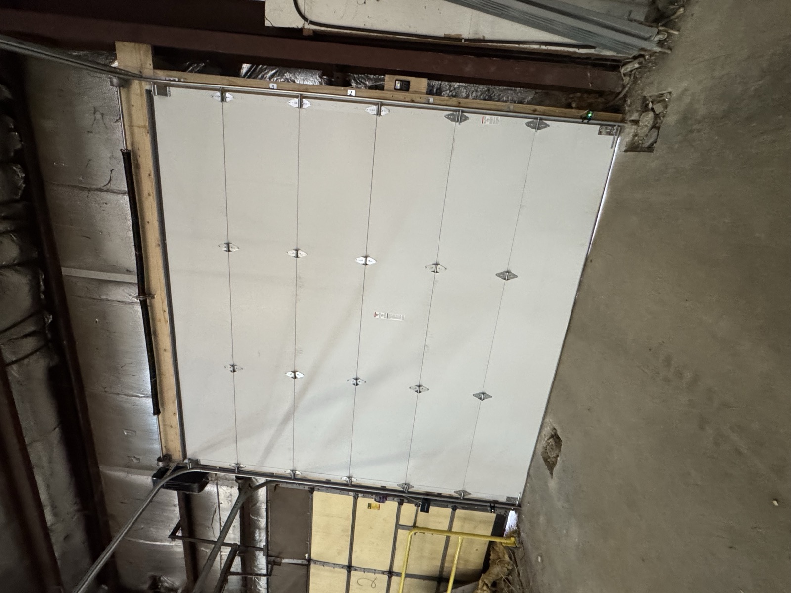 Wide commercial sectional garage door installed inside a pole barn structure