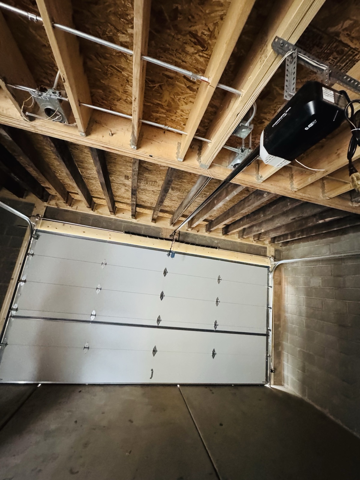 Garage door opener mounted to ceiling framing above a new garage door