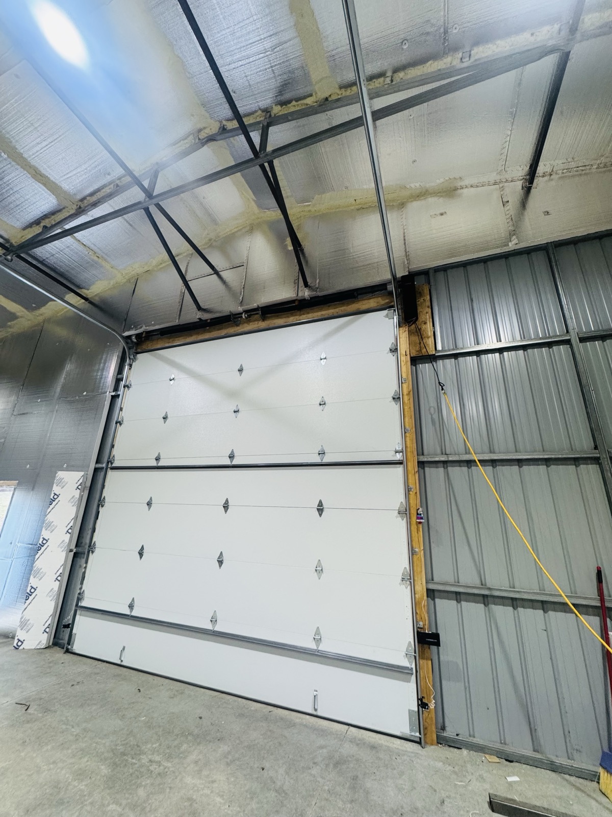 New white garage door installed inside a commercial pole barn building