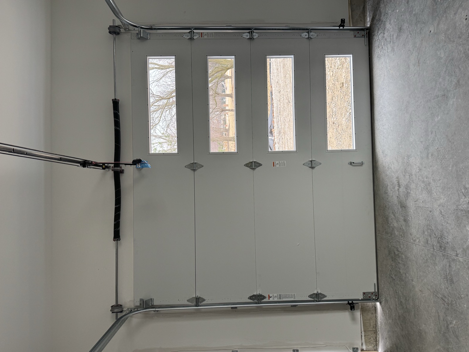 Tall sectional garage door with four window panels installed in a finished garage