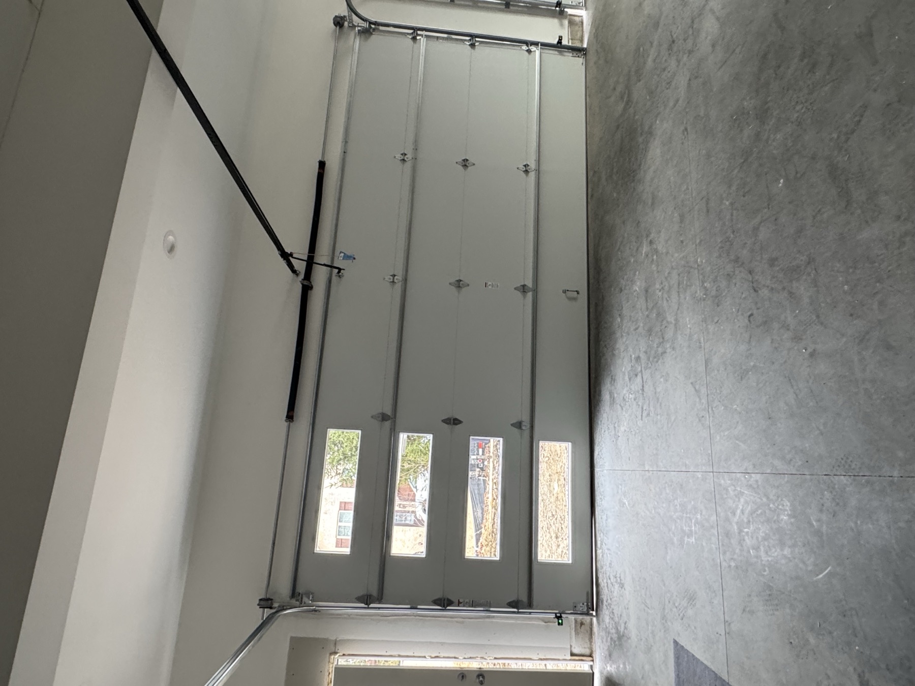 Newly installed garage door with window inserts, viewed from inside a finished garage